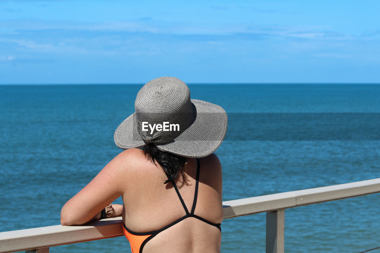 Rear view of woman standing at sea against sky