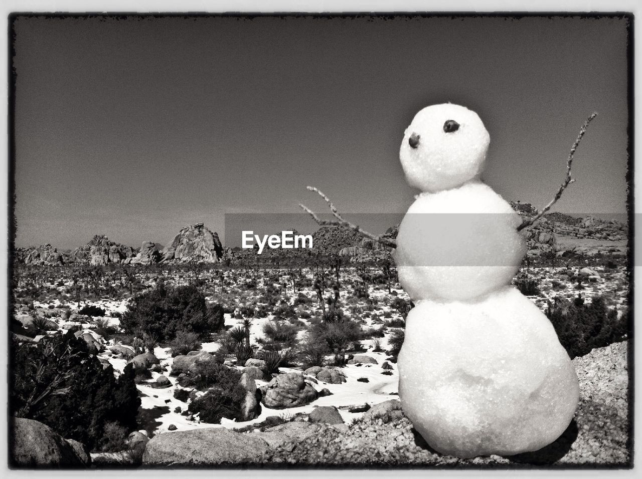 Snowman on rock against clear sky