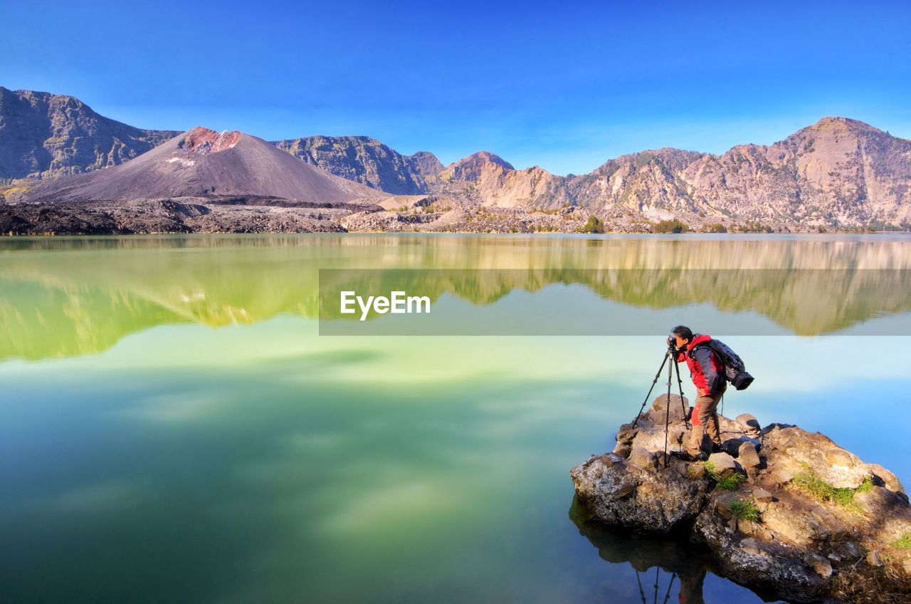 High angle view of man photographing while standing by lake 