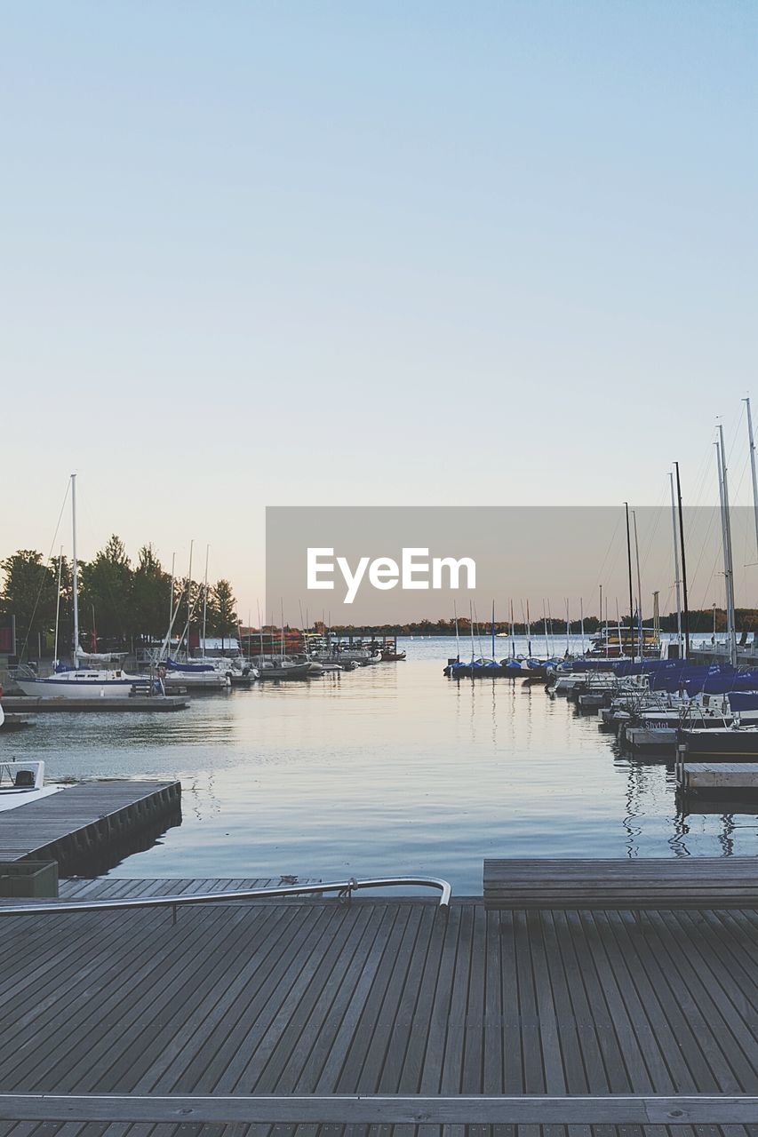 Boats moored at harbor against clear sky