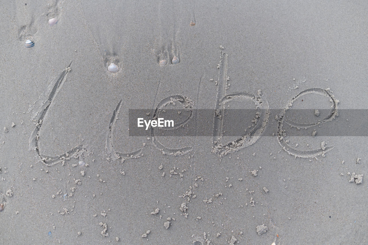 sand, beach, no people, text, wet, land, handwriting, western script, high angle view, nature, day, close-up, water, road surface, full frame, communication, outdoors, circle