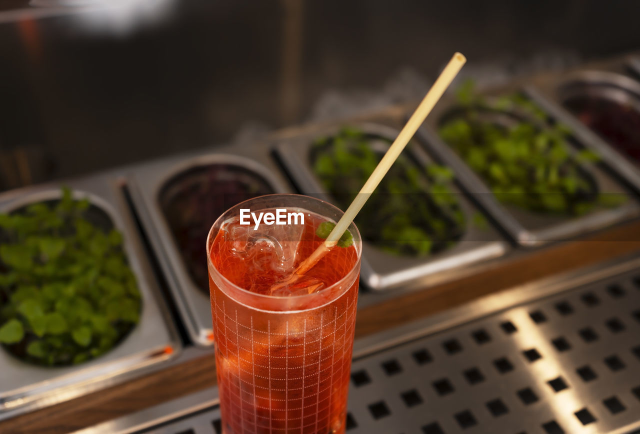 A glass of delicious red alcohol drink with a cocktail tube on a bar counter. night club drink.