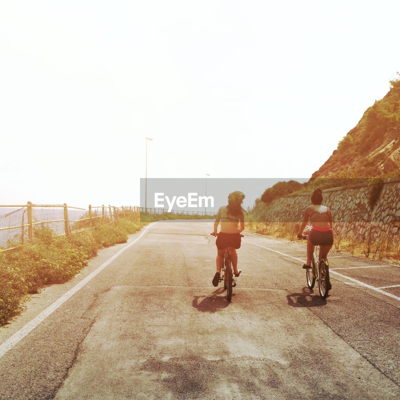 REAR VIEW OF MAN RIDING BICYCLE ON ROAD