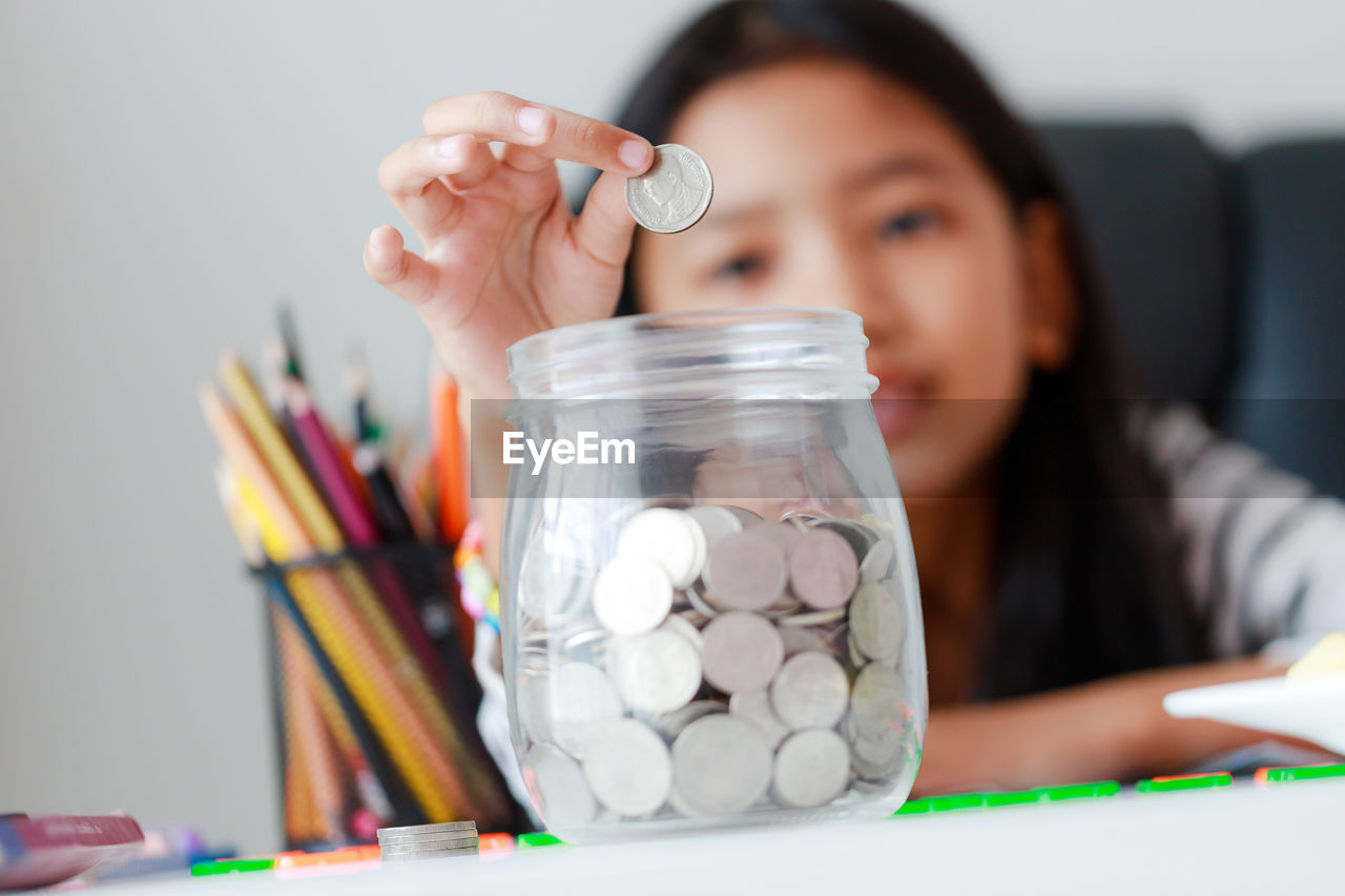 Portrait of girl putting coin in jar