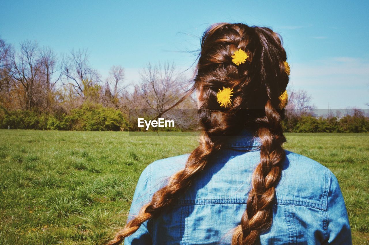 Rear view of woman wearing flowers on hair at grassy field