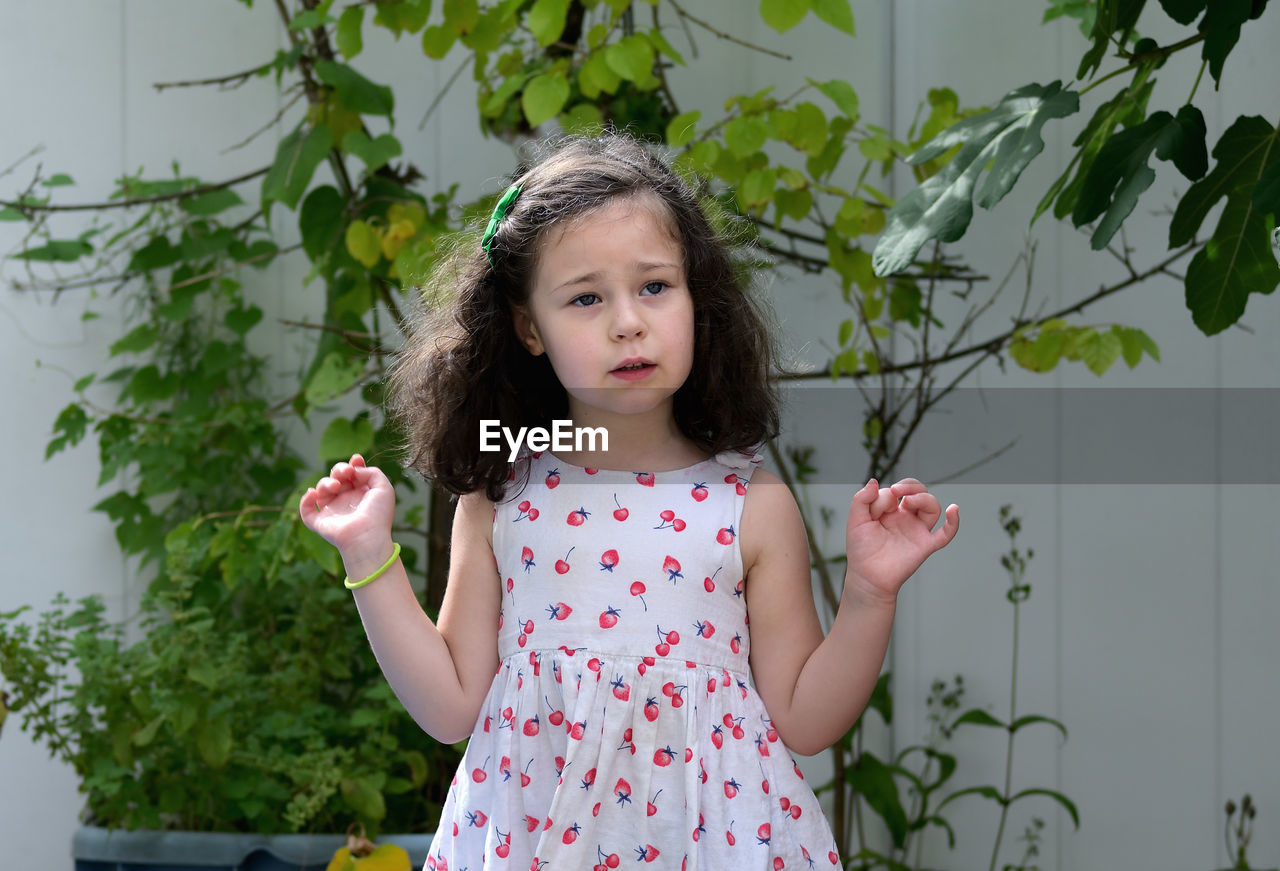 Expressive young girl in the summer dress enjoying the backyard