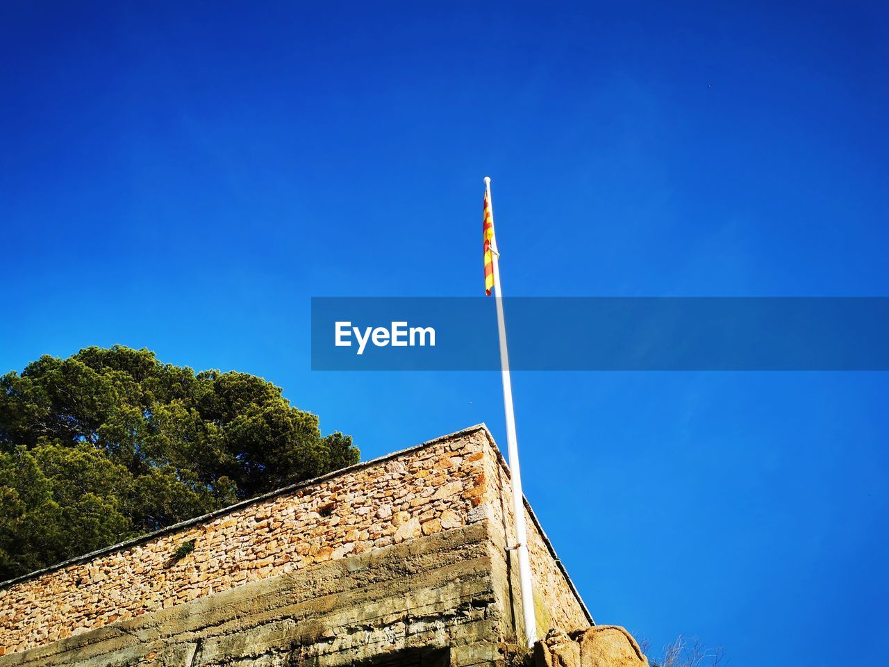 Low angle view of flag against clear blue sky