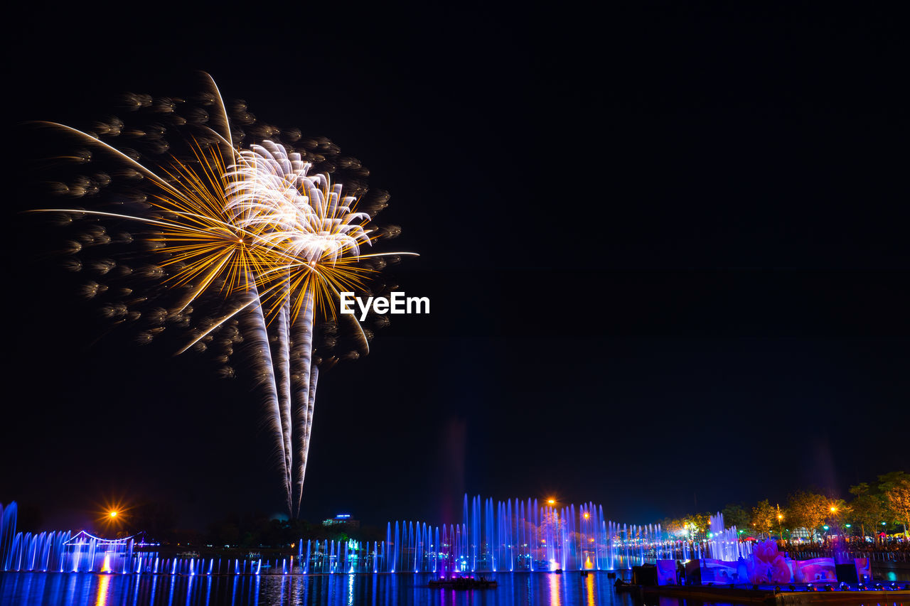 Fountain and fireworks display against sky