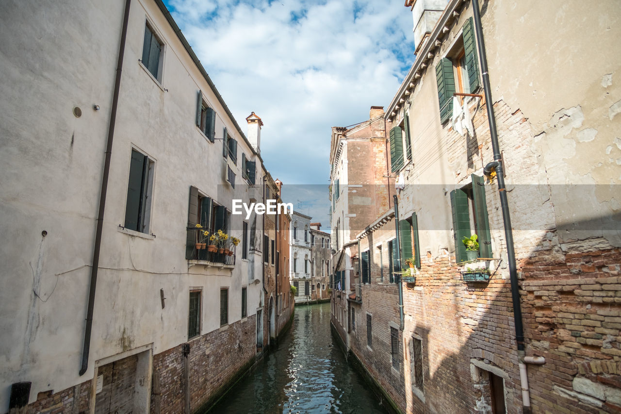 VIEW OF CANAL AMIDST BUILDINGS AGAINST SKY