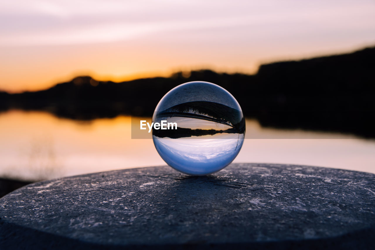 CLOSE-UP OF CRYSTAL BALL WITH REFLECTION IN LAKE