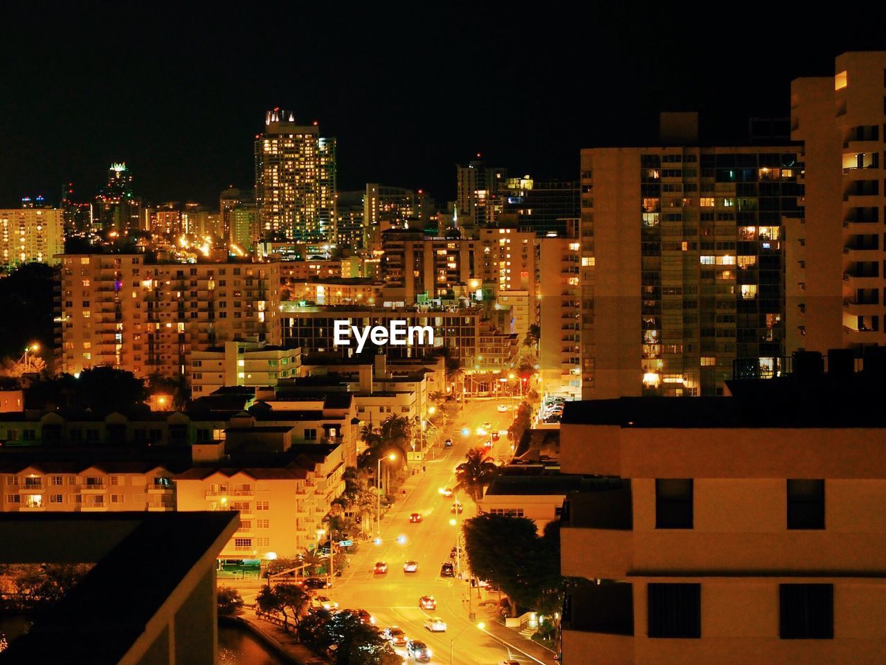 Vehicles on road along illuminated buildings