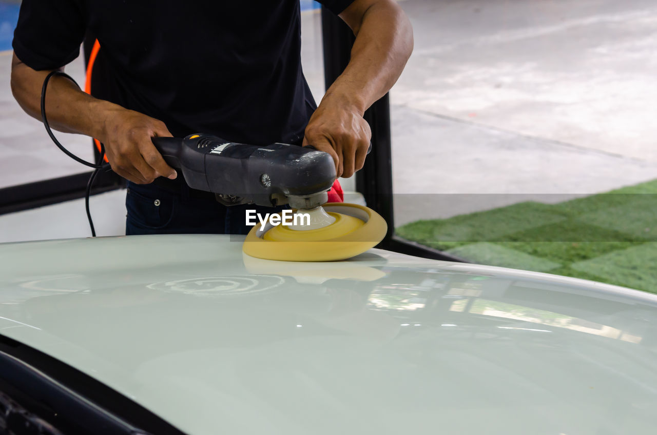 Cropped hands of mechanic polishing car in garage