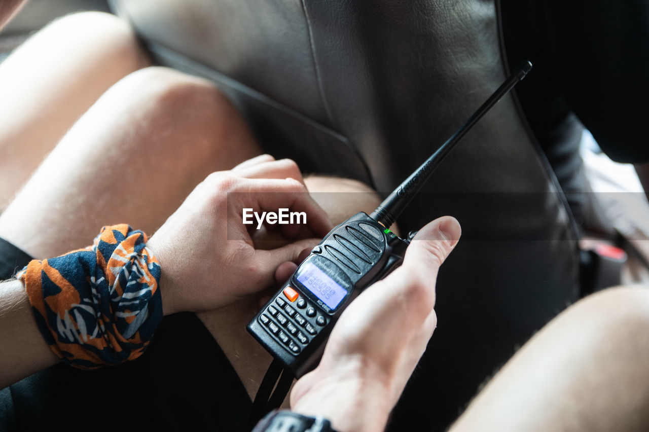 Midsection of man holding walkie-talkie in car