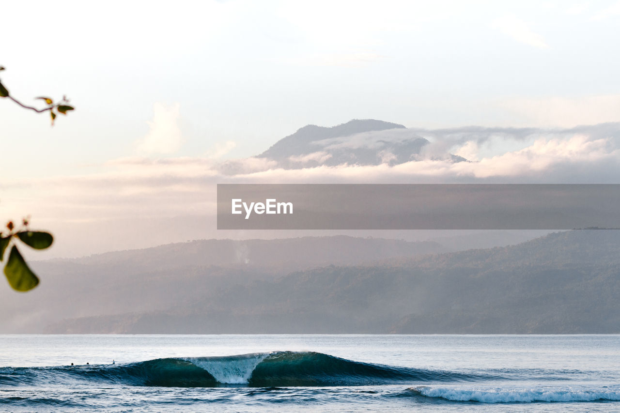 Scenic view of sea against mountains during sunset