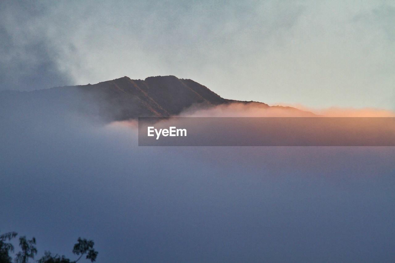 Low angle view of volcanic mountain against sky during sunset