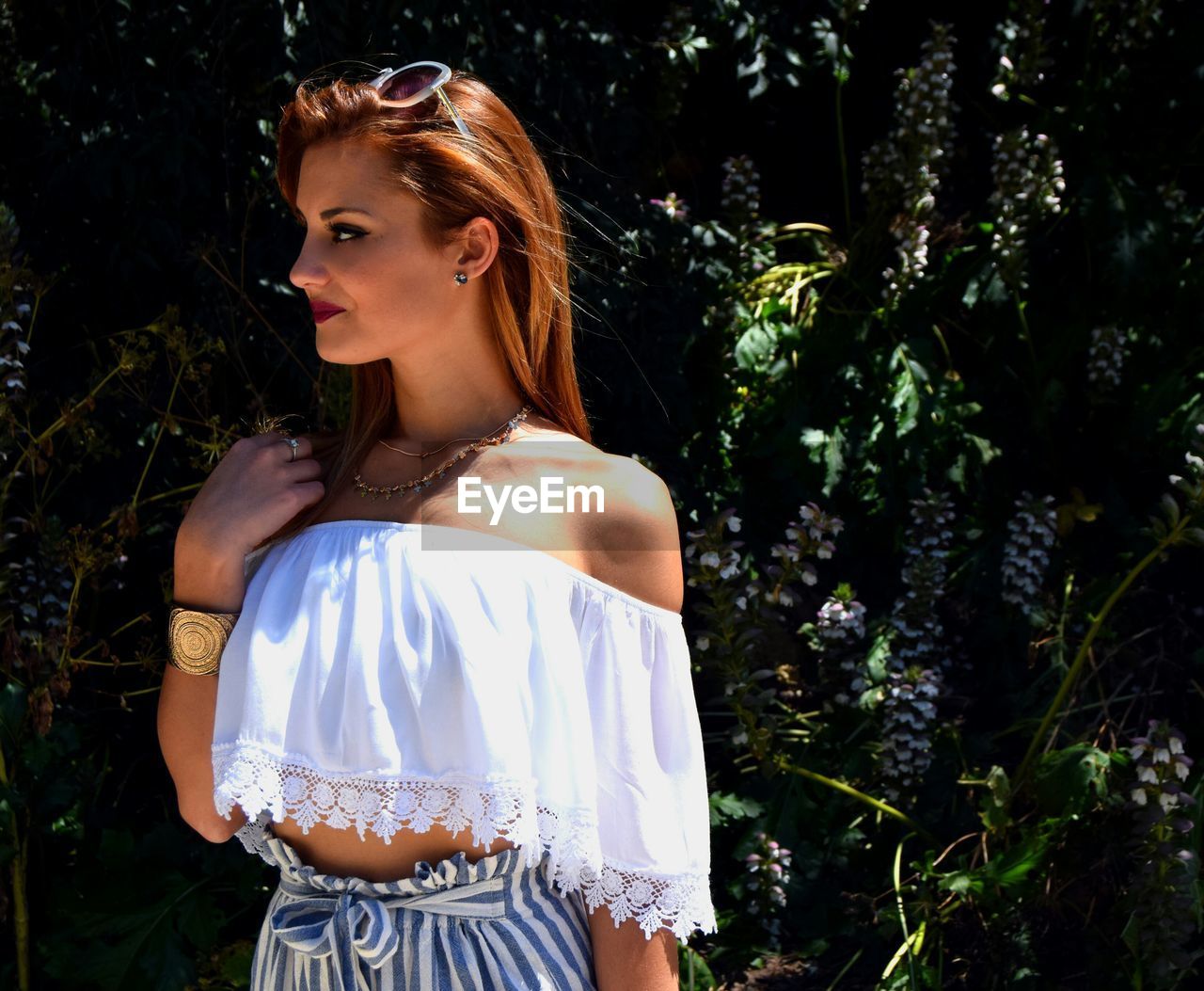 Fashionable young woman looking away while standing against plants