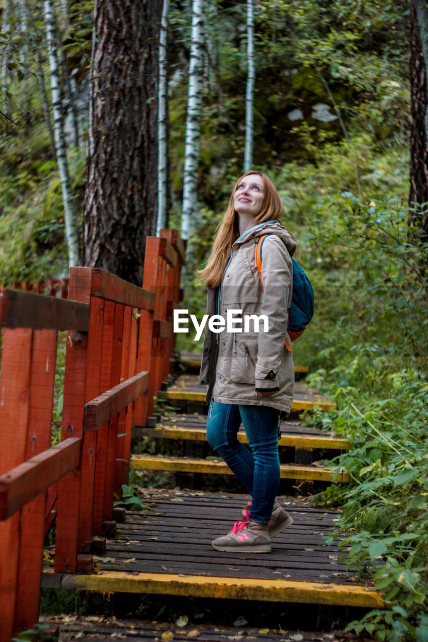 Side view of woman standing on steps in forest