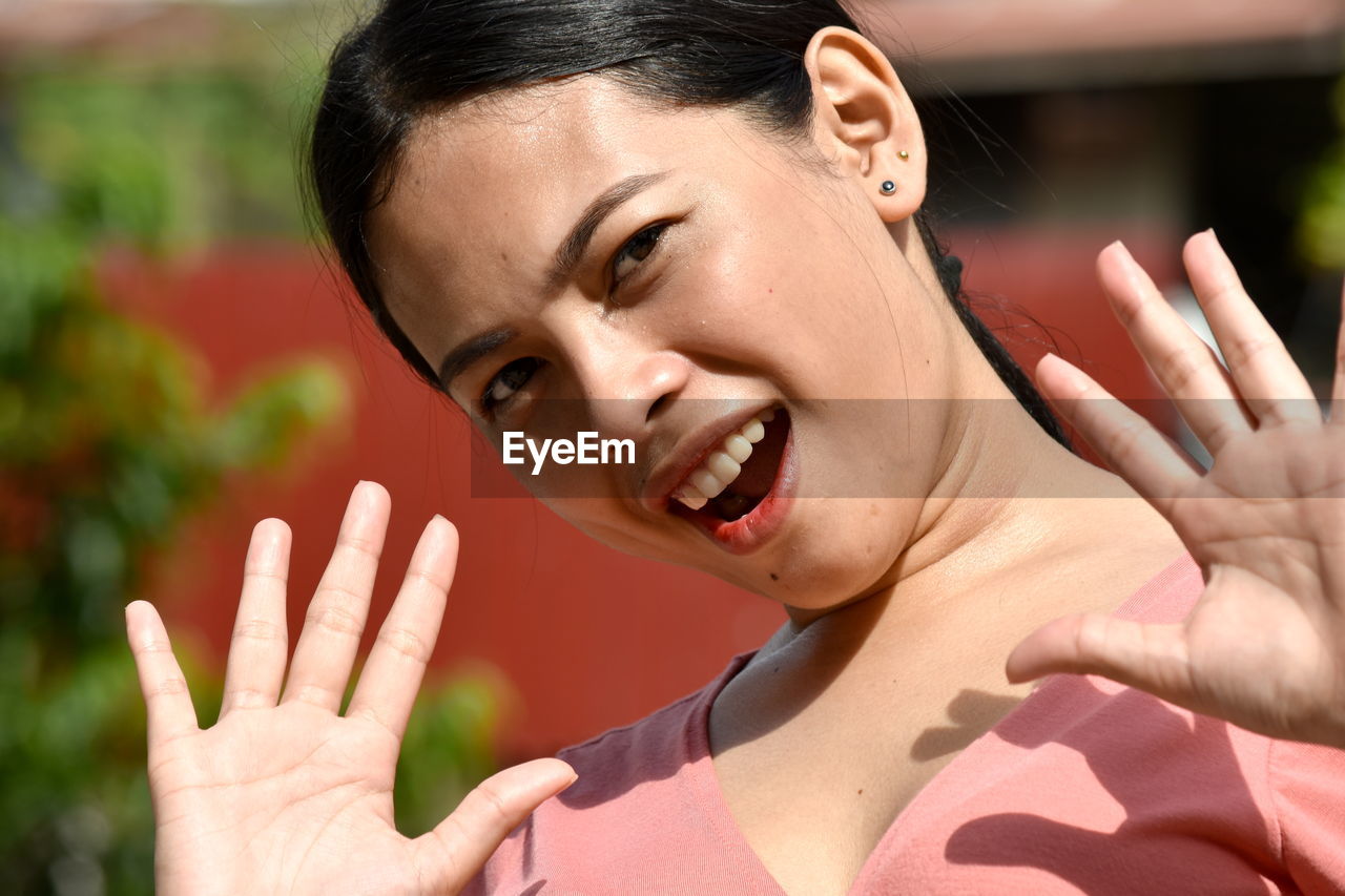 Close-up portrait of smiling woman gesturing outdoors