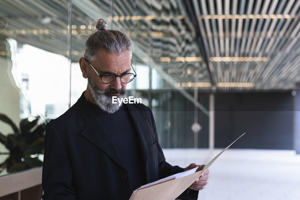 Businessman reading file in front of building