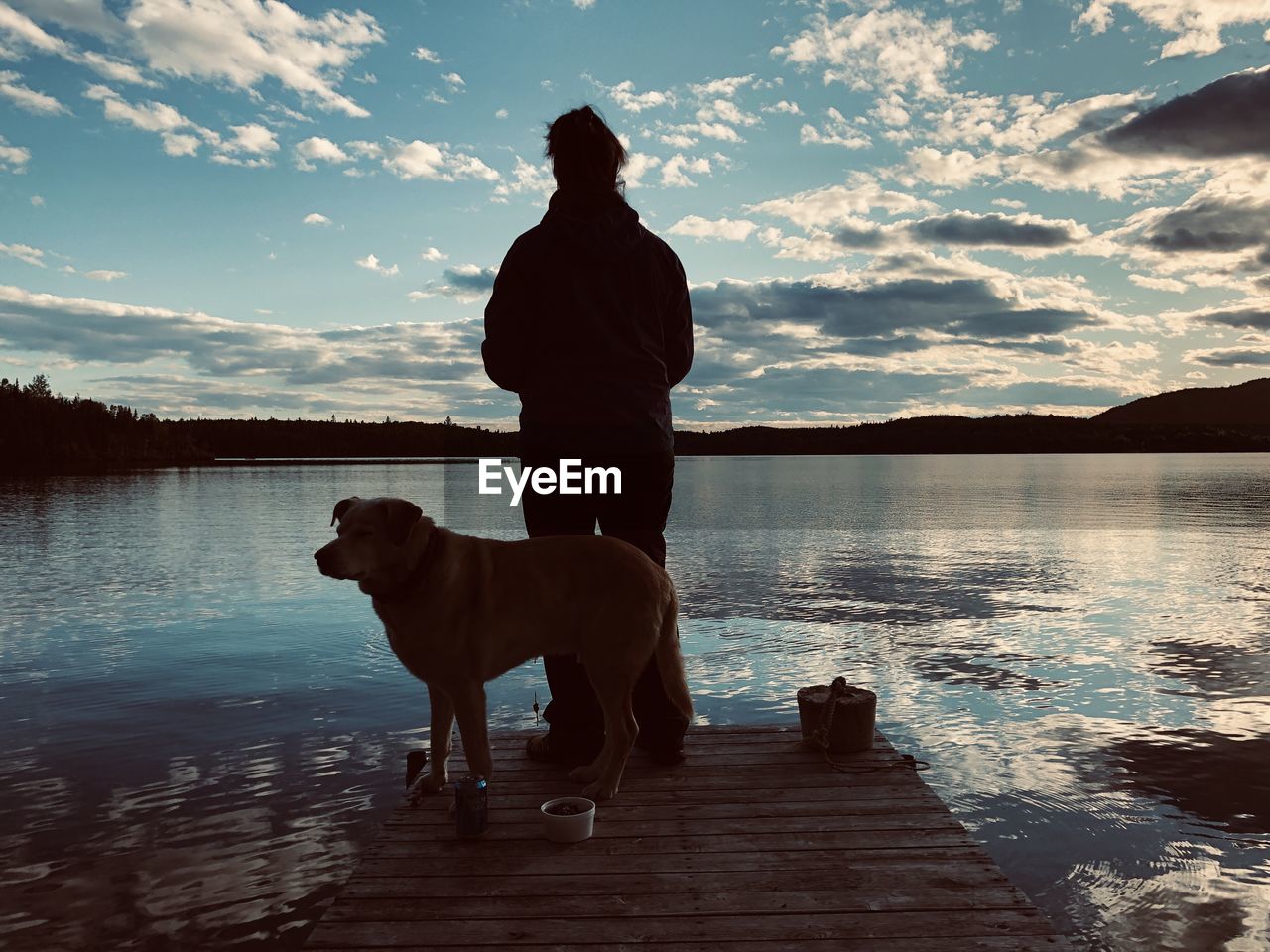 WOMAN WITH DOG STANDING IN LAKE
