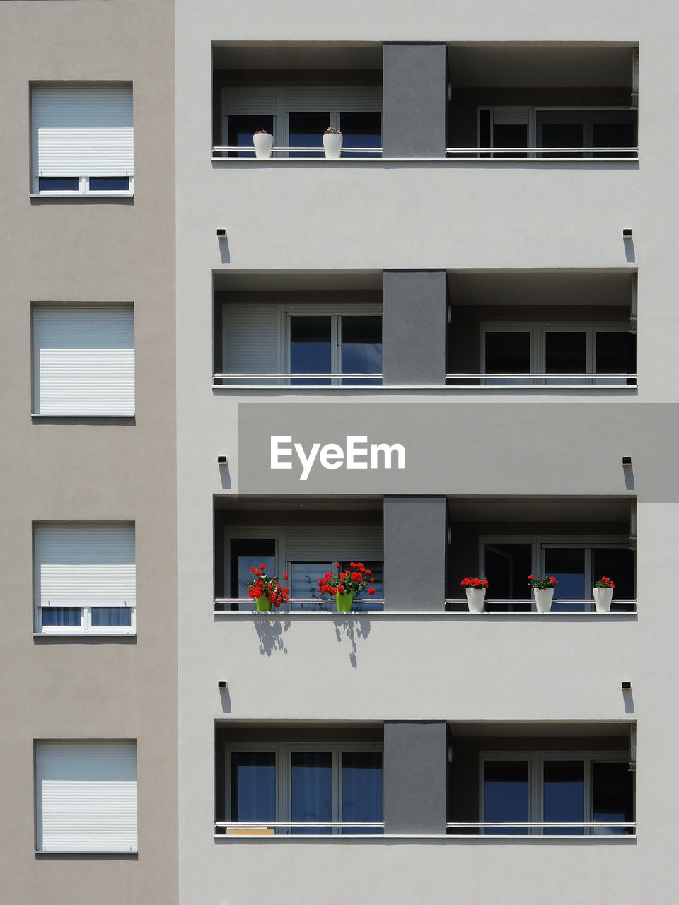 Facade of the modern apartment building, one balcony with flowers