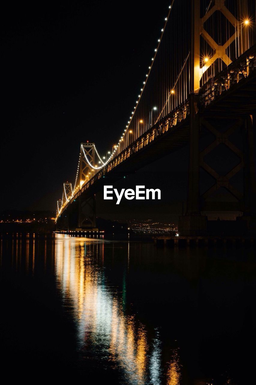 Illuminated bridge over sea at night