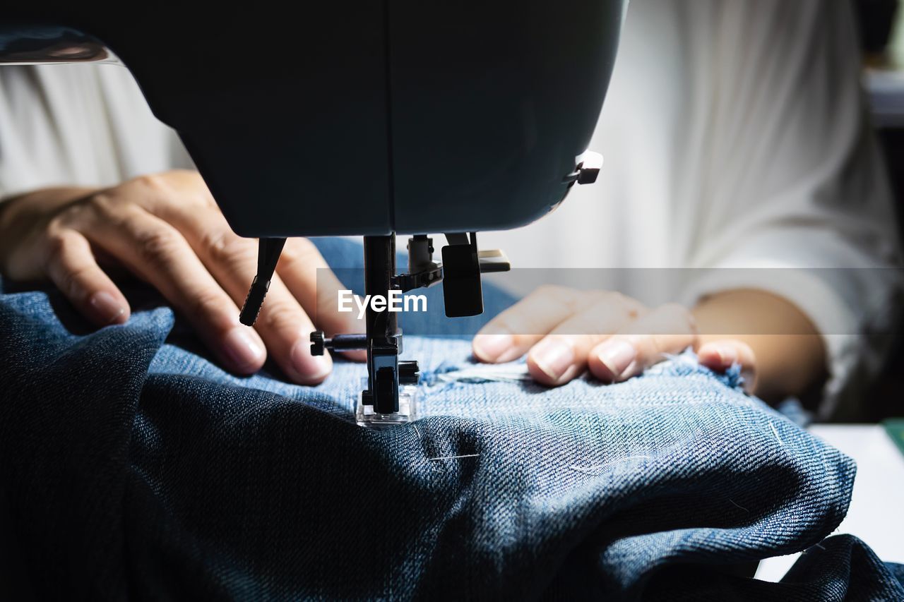 Midsection of woman stitching clothes on sewing machine