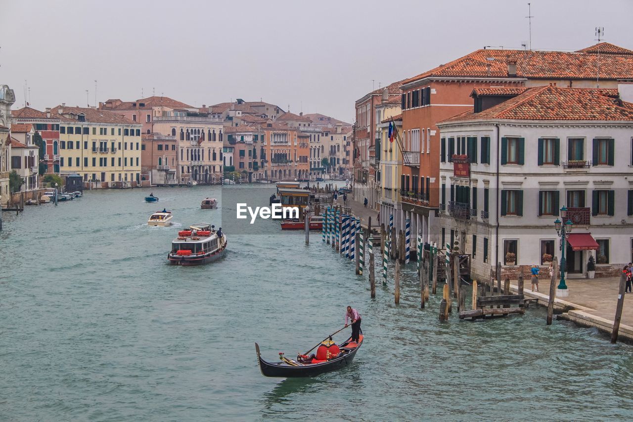 BOATS IN CANAL AMIDST BUILDINGS IN CITY