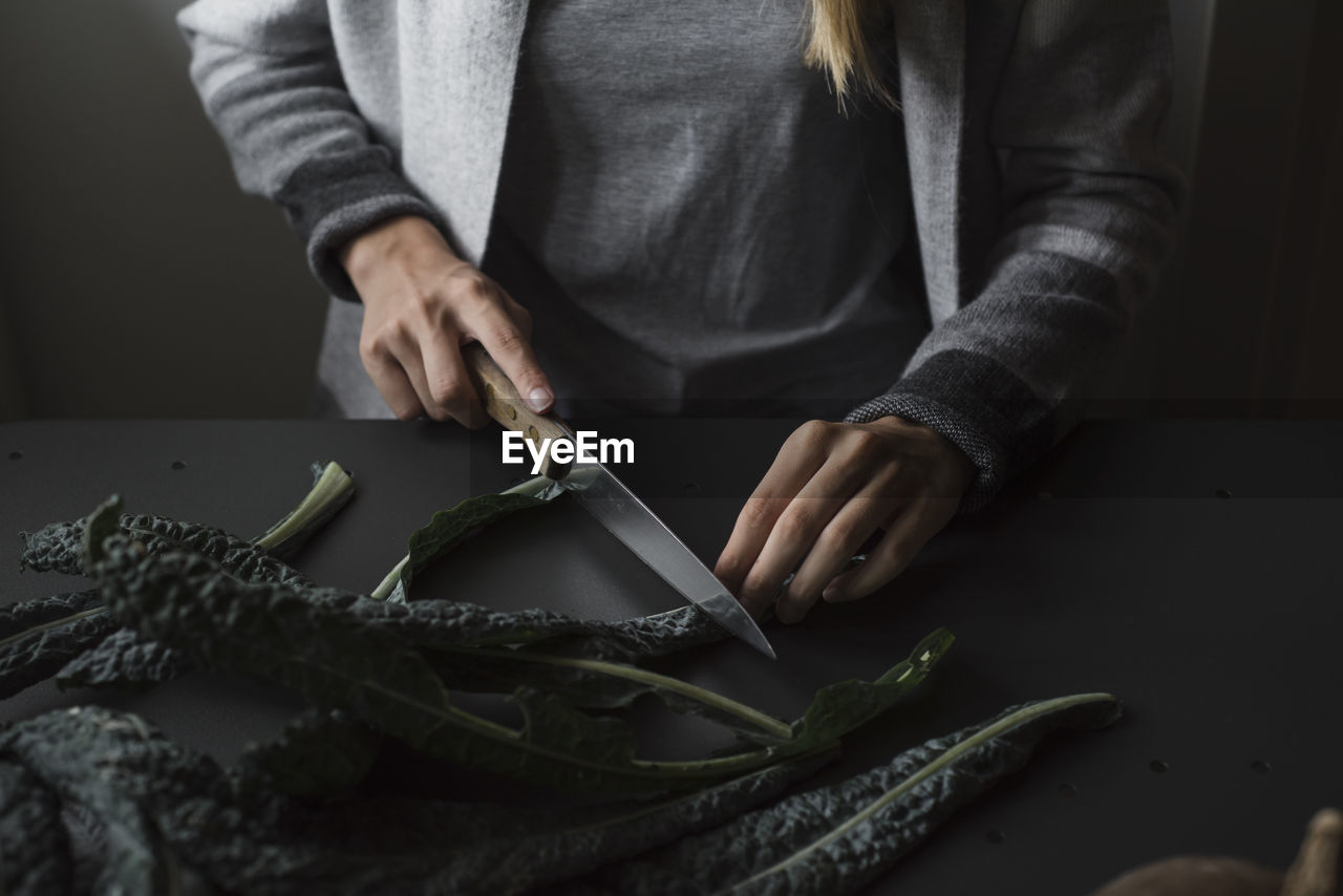 Midsection of woman cutting leaves 