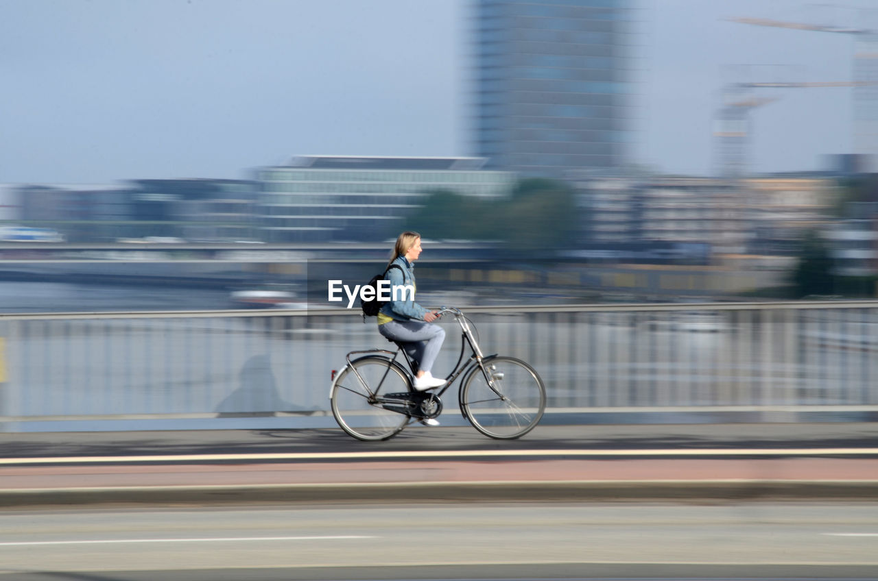 Blurred motion of woman riding bicycle on road in city