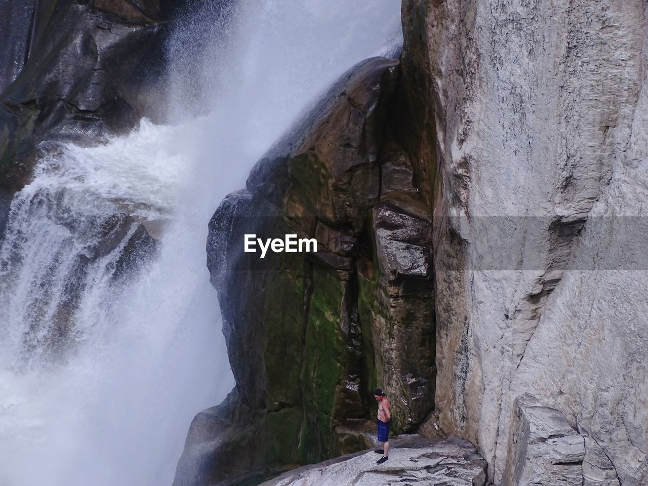 Man standing on mountain by waterfall