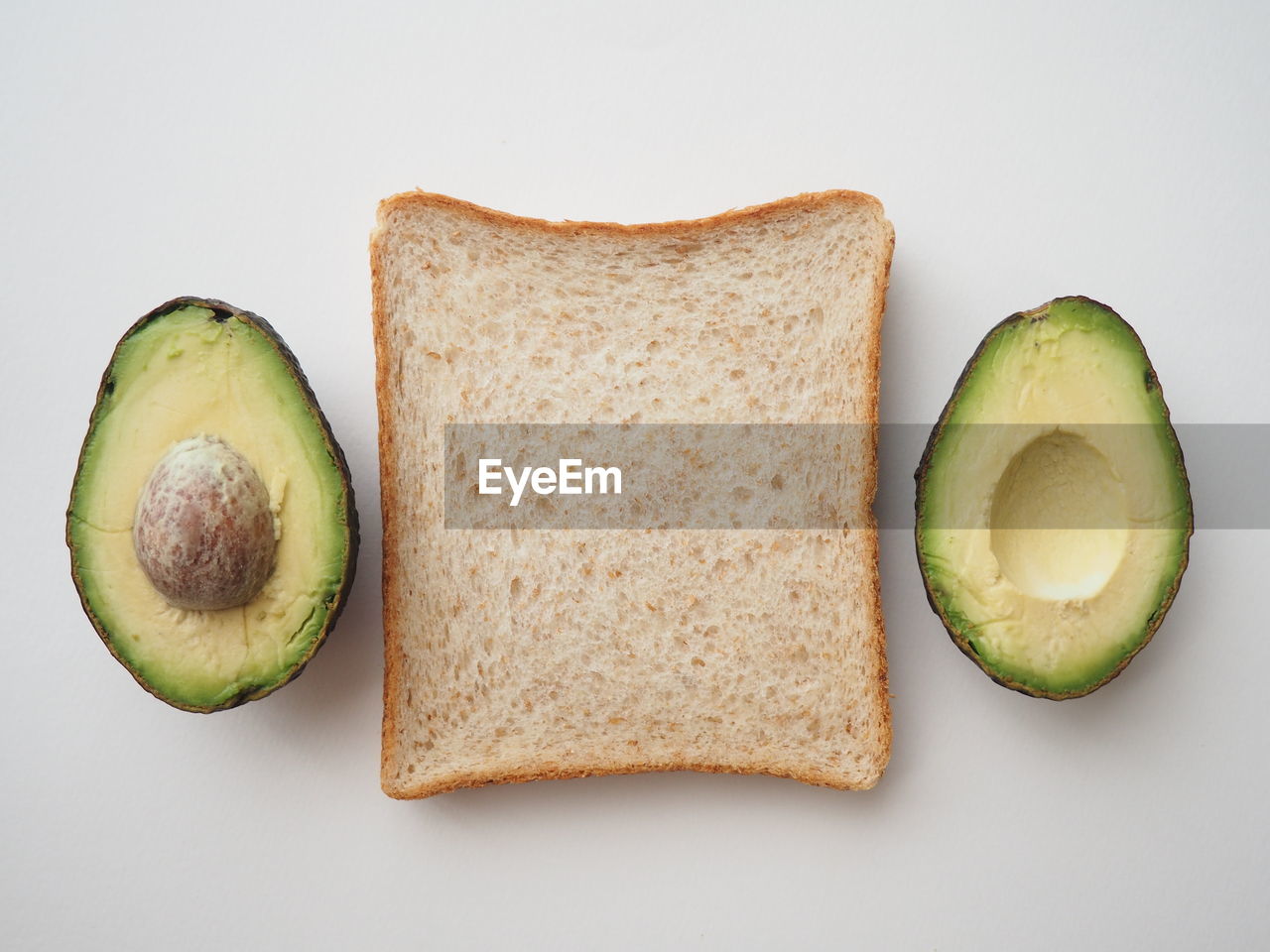 Directly above shot of breakfast with  whole wheat bread and avocado on white background