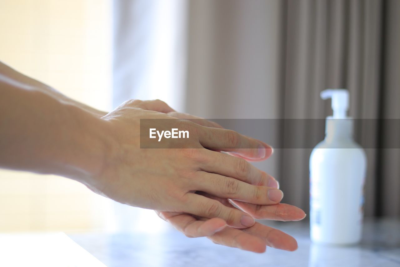 CLOSE-UP OF MAN HAND HOLDING BOTTLE WITH REFLECTION