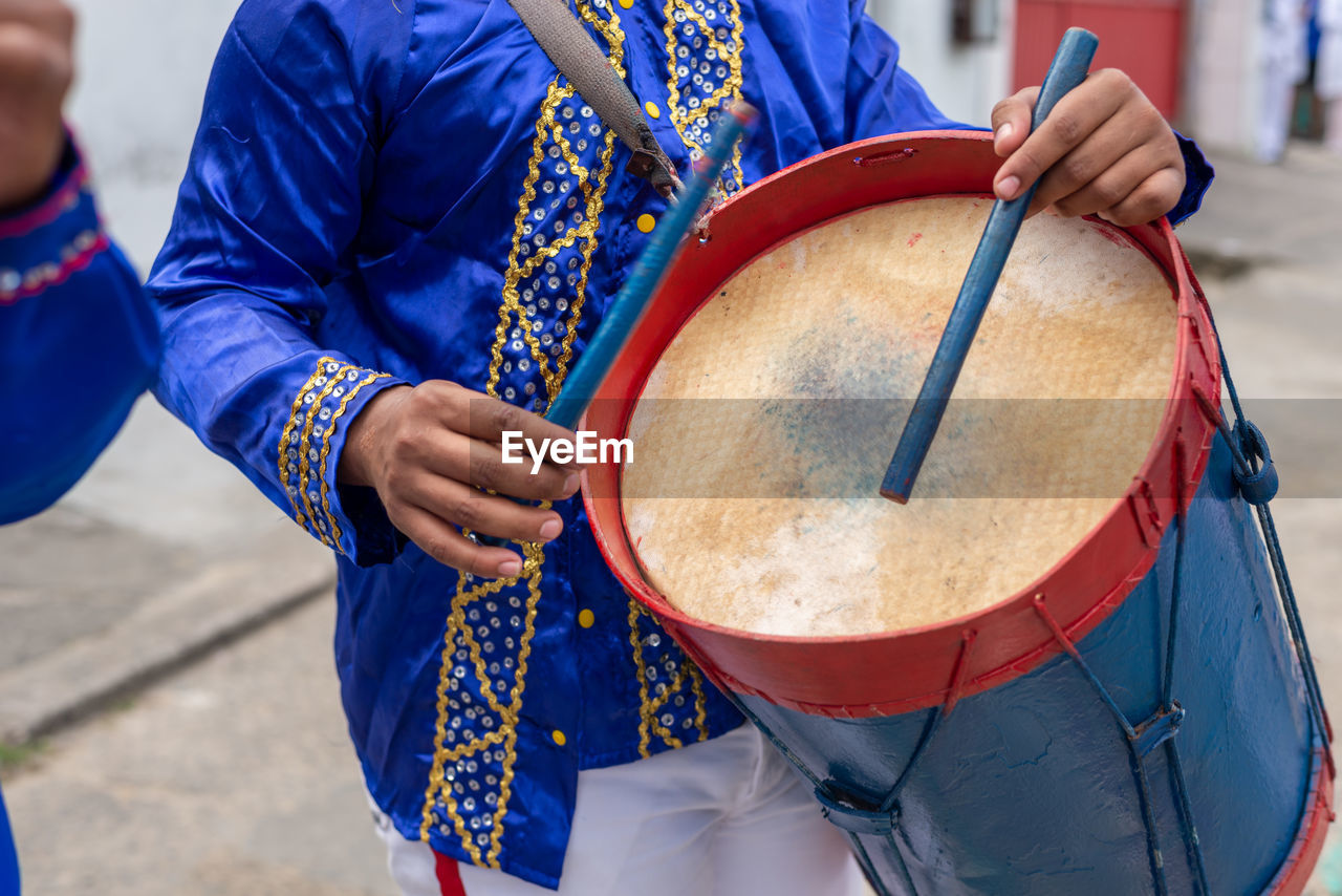 Members of a marujada, dressed in blue, play percussion instruments 