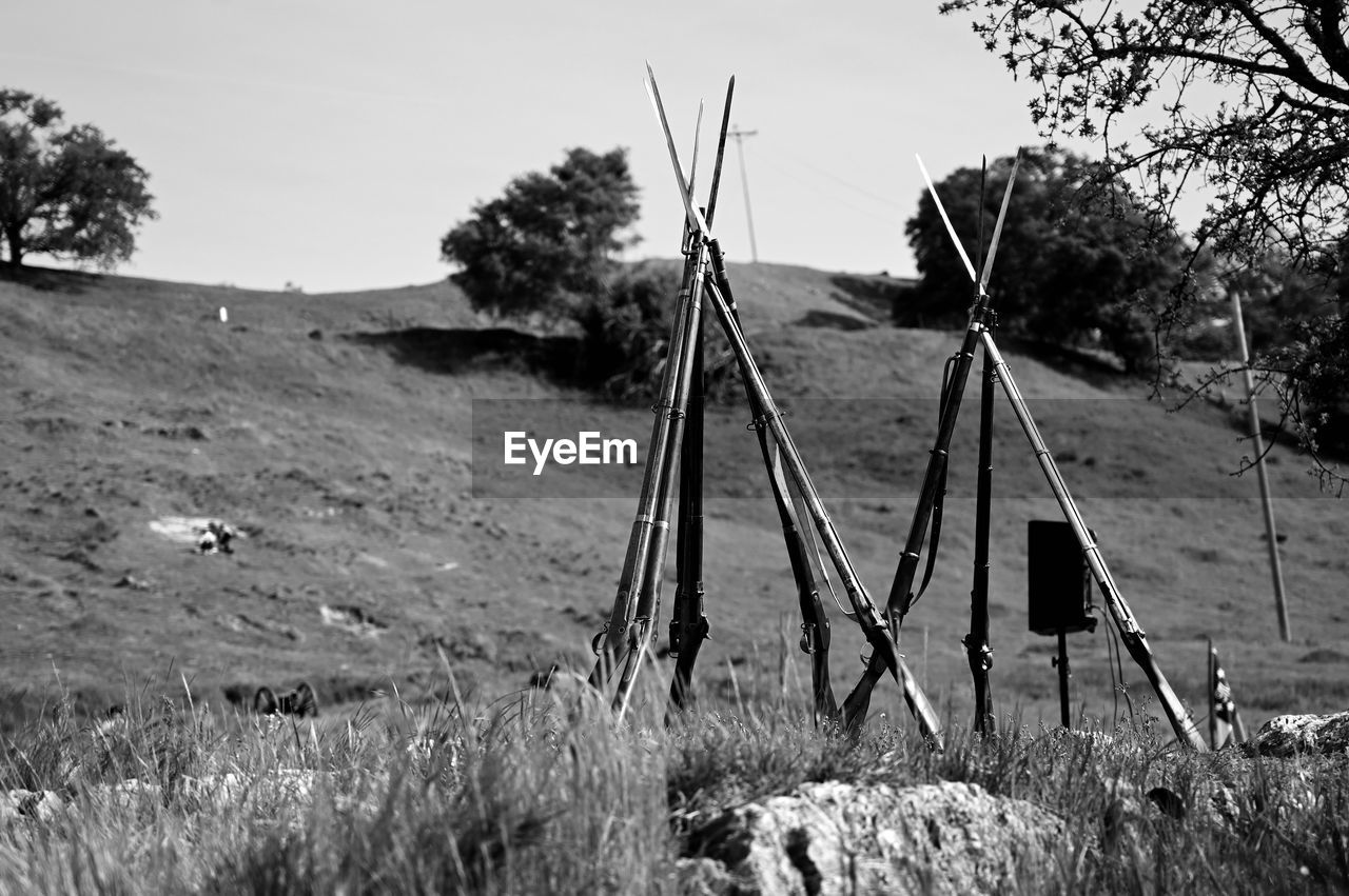 Close-up of guns on the field against sky