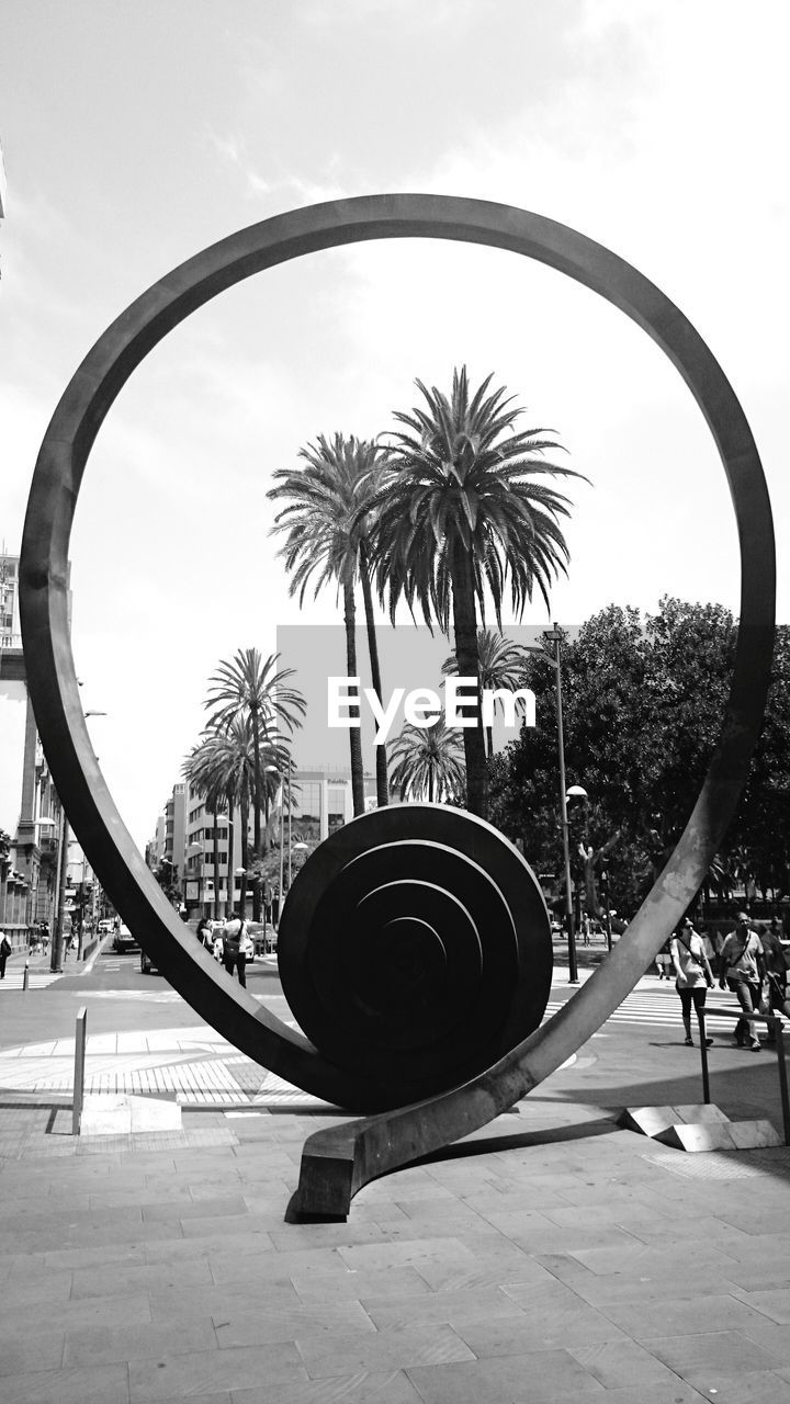 Palm trees seen through sculpture on sidewalk