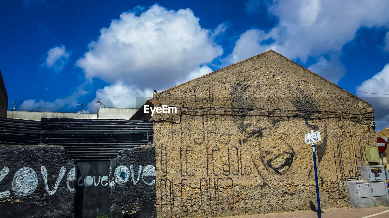 LOW ANGLE VIEW OF WALL AGAINST CLOUDY SKY