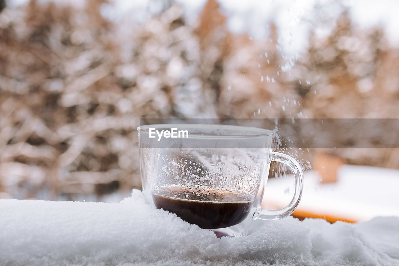 CLOSE-UP OF COFFEE CUP ON ICE CREAM IN SNOW