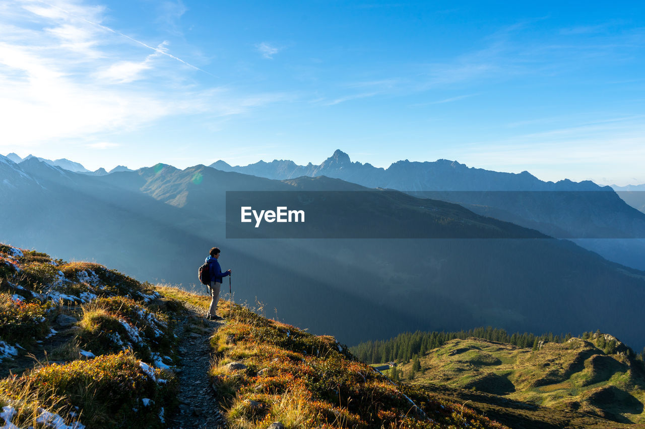 Mature woman standing on mountain against blue sky