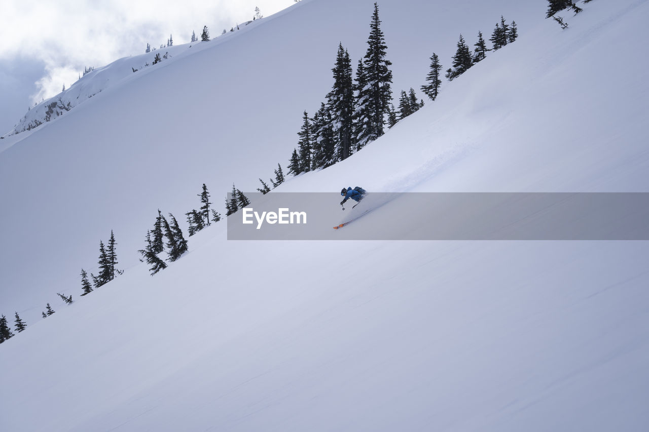 Low angle view of person skiing on snowcapped mountain against sky