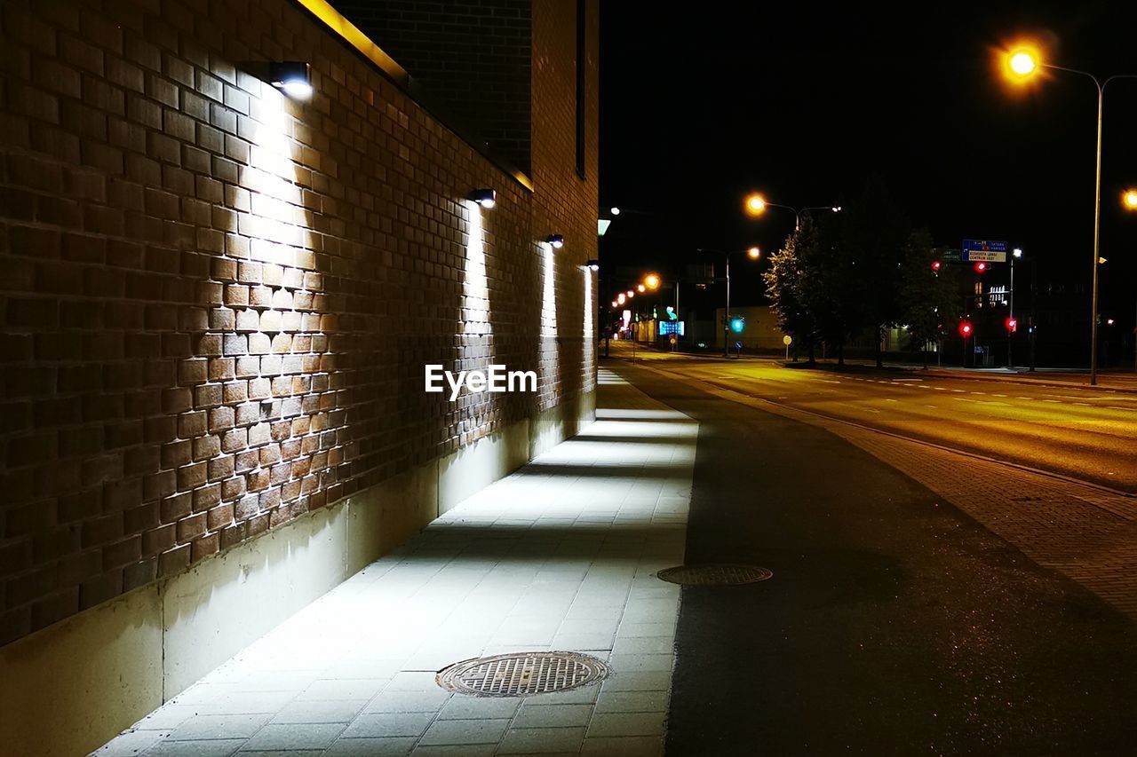 EMPTY ROAD ALONG ILLUMINATED STREET LIGHTS