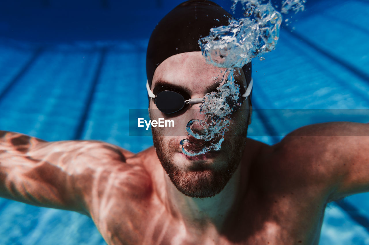 Young male swimmer diving in swimming pool