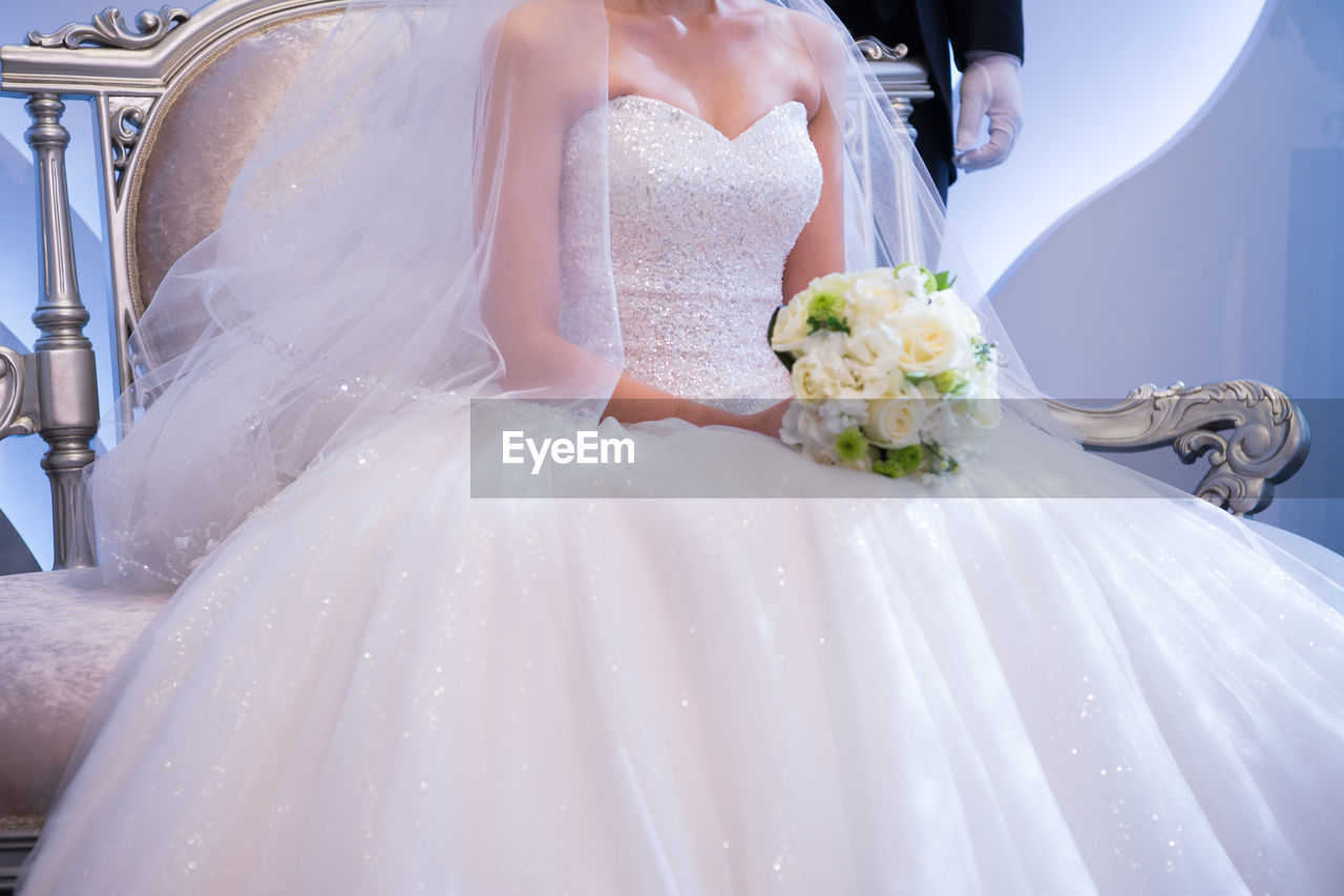 Midsection of bride holding bouquet