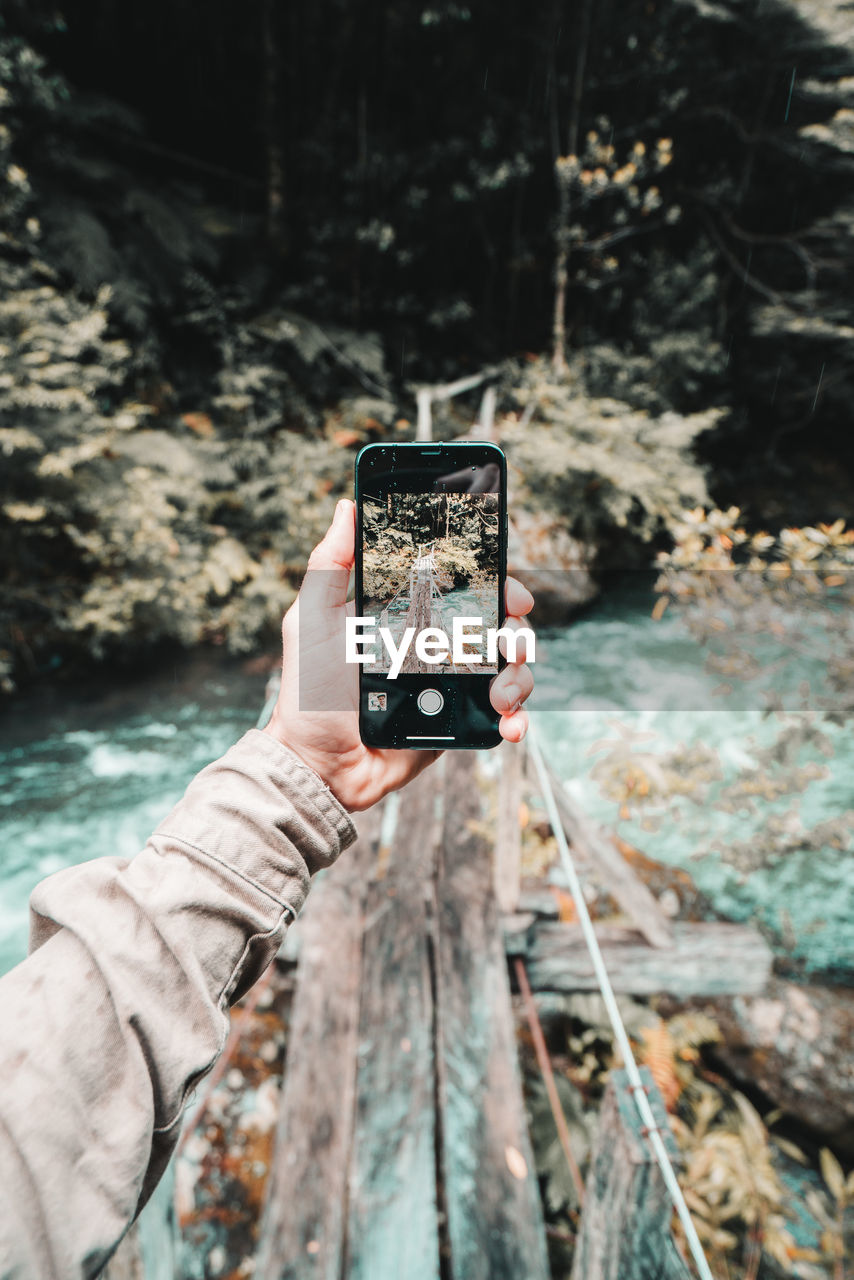 Wide angle fpv of hiker photographing bridge with smartphone