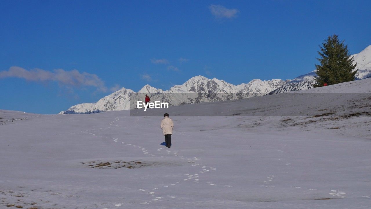 rear view of woman walking on snow covered mountain