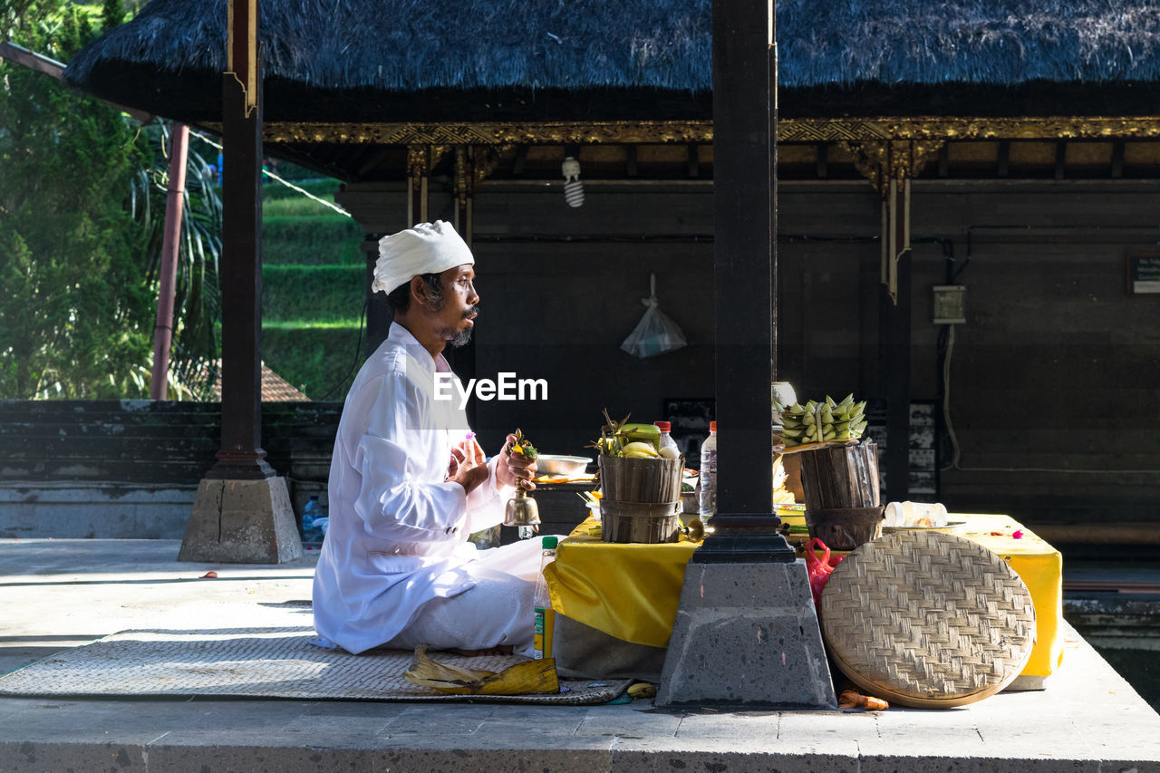 REAR VIEW OF A MAN SITTING AT THE PARK