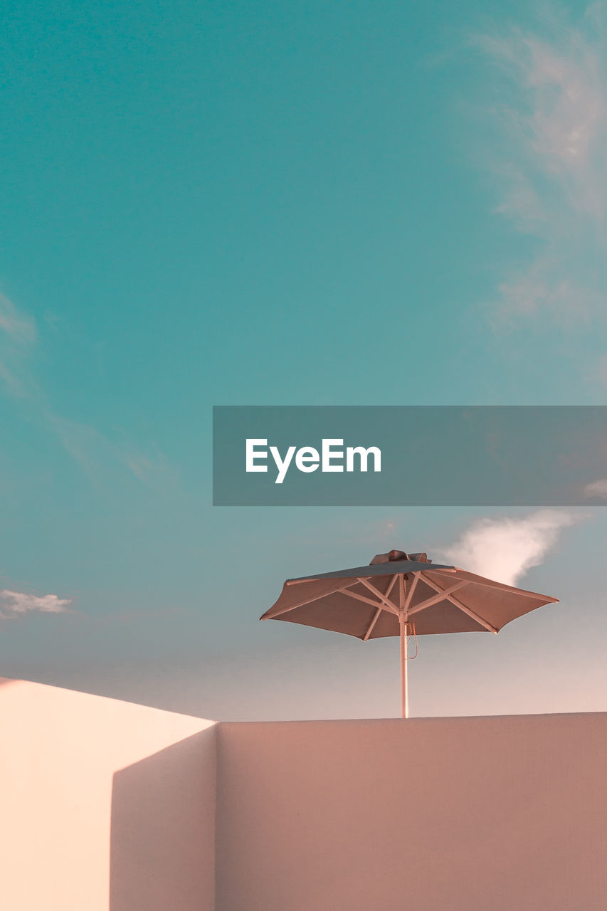 Low angle view of umbrella on building against blue sky