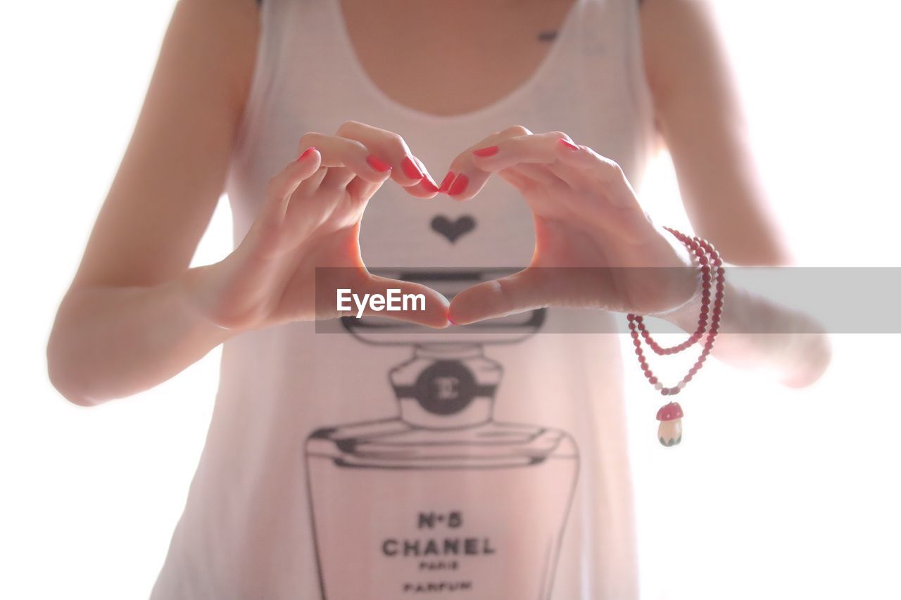 CLOSE-UP OF WOMAN HAND HOLDING HEART SHAPE AGAINST WHITE BACKGROUND