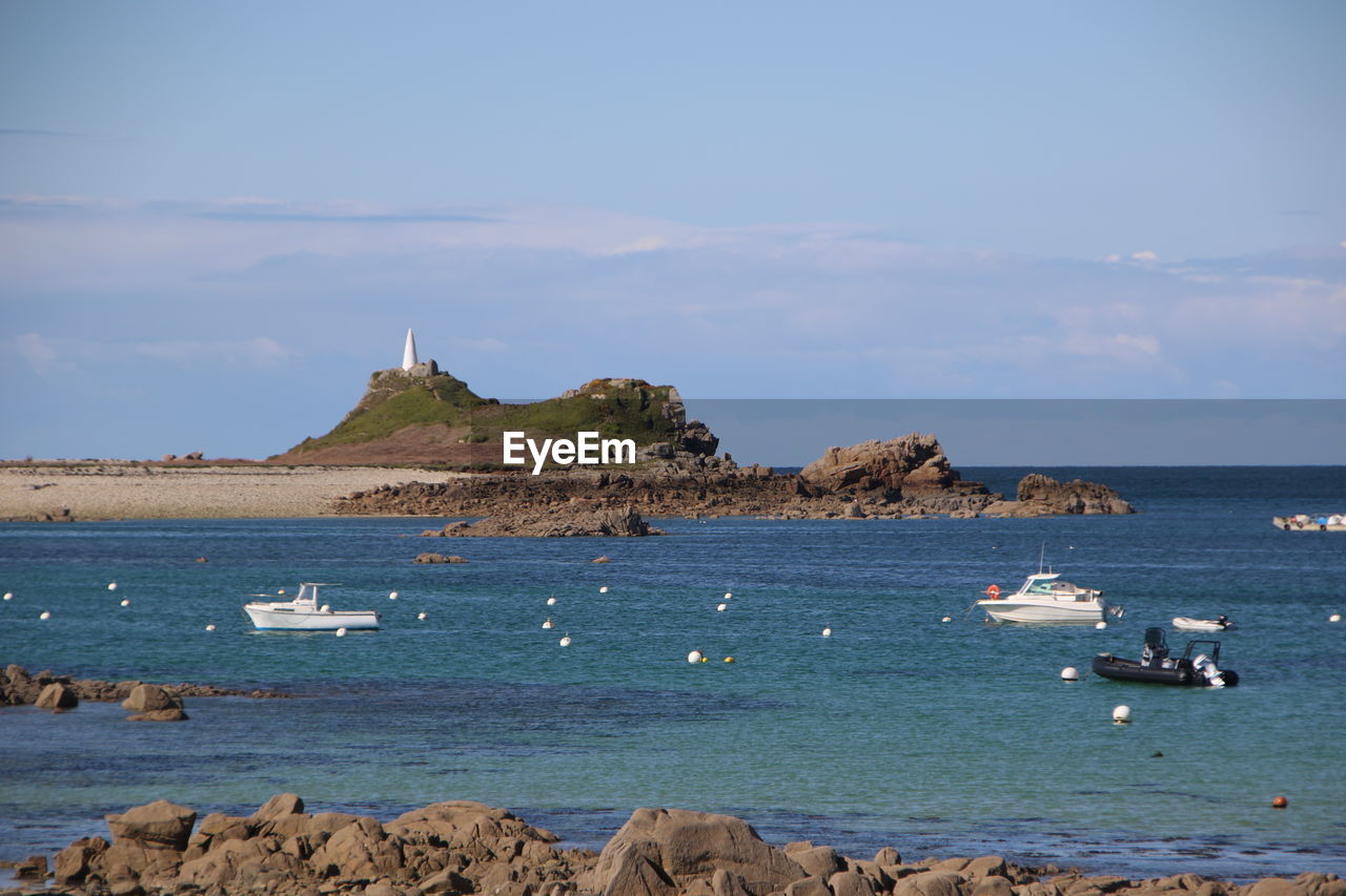 Sailboats on sea shore against sky
