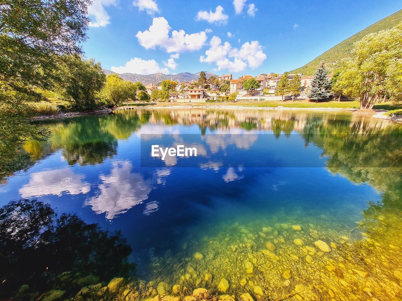 SCENIC VIEW OF LAKE BY TREES AGAINST BLUE SKY